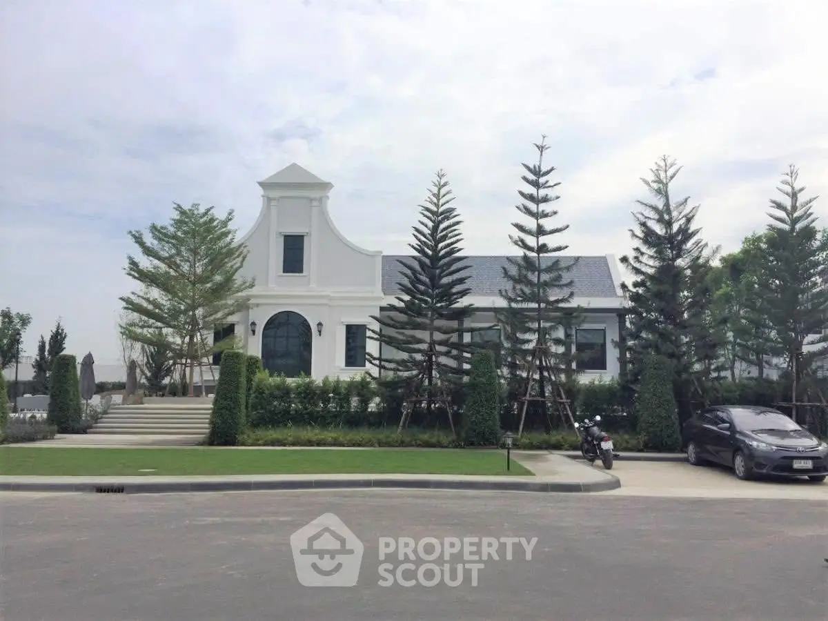 Charming white house with lush landscaping and modern design in a serene neighborhood.