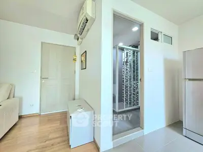 Modern apartment interior with air conditioning, wooden flooring, and a compact kitchen area.