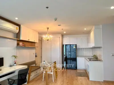 Modern open-plan living room and kitchen with elegant chandelier and sleek appliances.