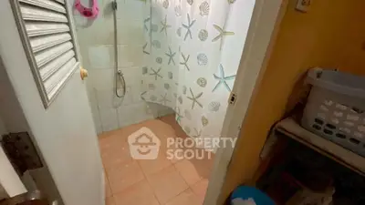 Cozy bathroom with tiled floor and seashell-themed shower curtain, perfect for a beach-inspired home.