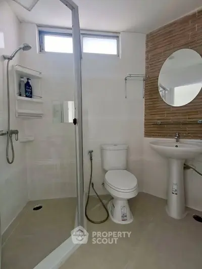 Modern bathroom with glass shower, toilet, and stylish sink in a bright setting.