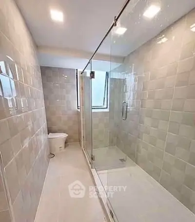 Modern bathroom with glass shower enclosure and sleek tile design.