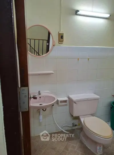 Cozy bathroom with pink fixtures and tiled walls, featuring a compact sink and toilet.