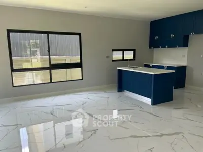 Modern kitchen with sleek blue cabinets and marble flooring, featuring an open layout and large windows.