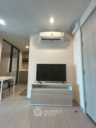 Modern living room with sleek TV setup and air conditioning in a stylish apartment.