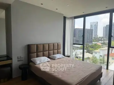 Modern bedroom with large windows offering stunning city views in a high-rise apartment.