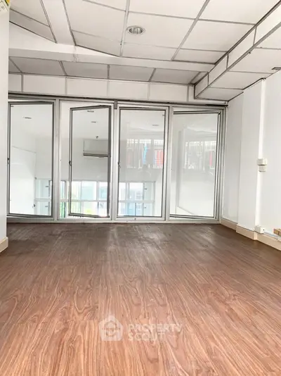 Spacious room with wooden flooring and glass doors, perfect for versatile use.