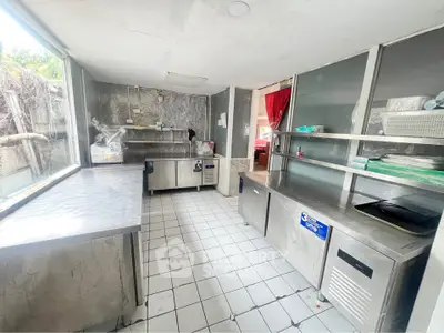 Spacious commercial kitchen with stainless steel counters and ample natural light.