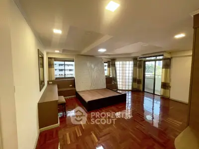 Spacious bedroom with hardwood floors and large windows in modern apartment