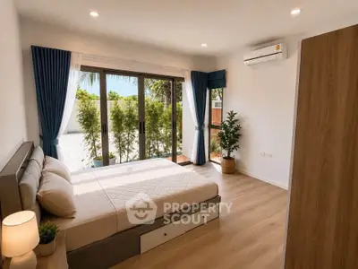 Spacious bedroom with large windows and garden view, featuring modern decor and natural light.