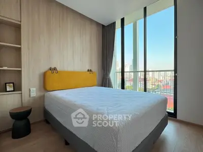 Modern bedroom with large windows and city view, featuring stylish decor and ample natural light.