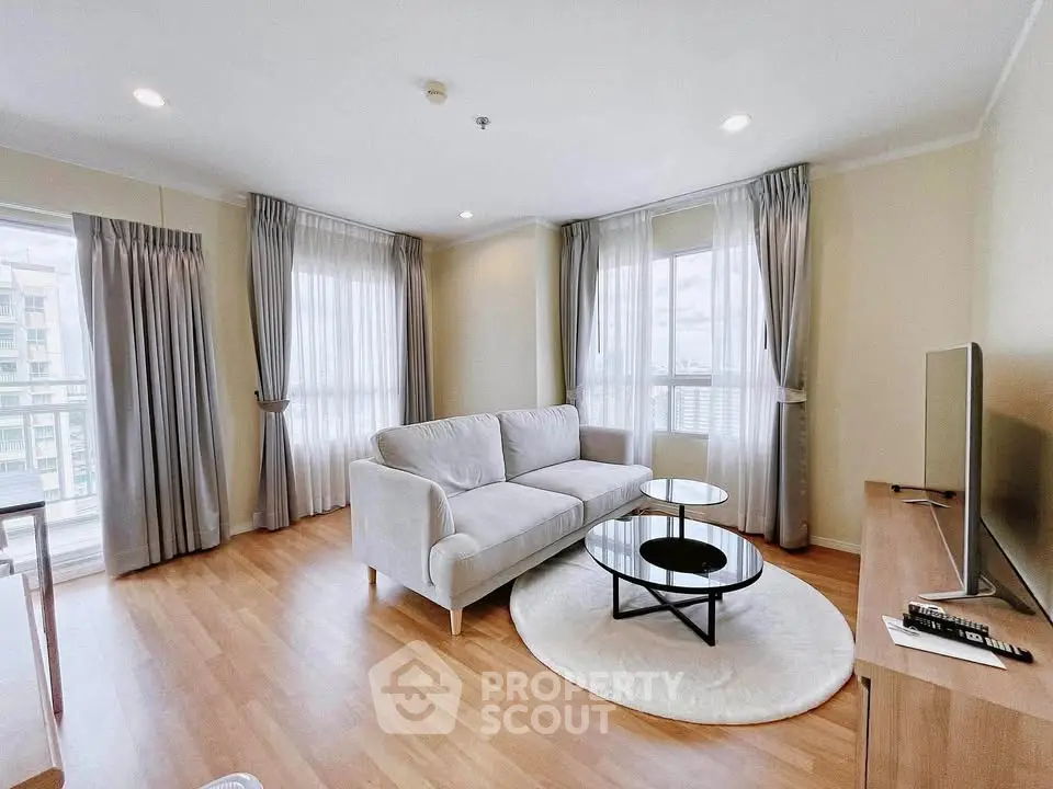 Spacious living room with modern decor and large windows in a high-rise apartment.
