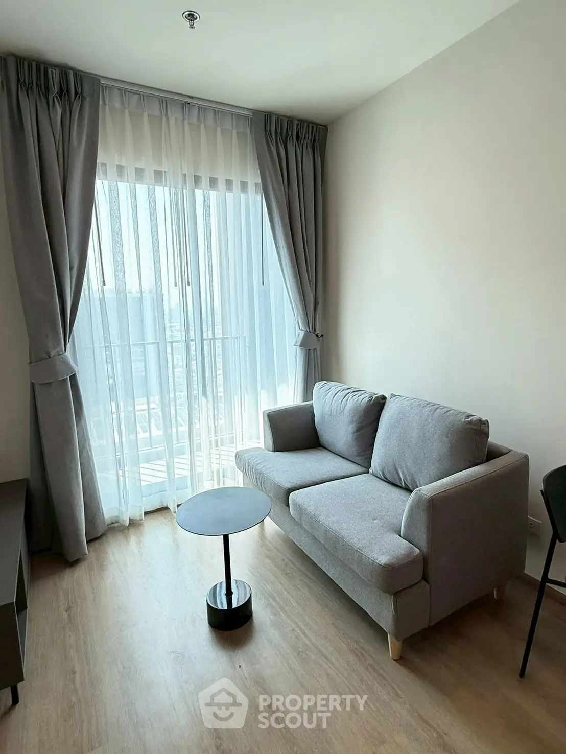 Modern living room with stylish gray sofa and floor-to-ceiling window curtains.