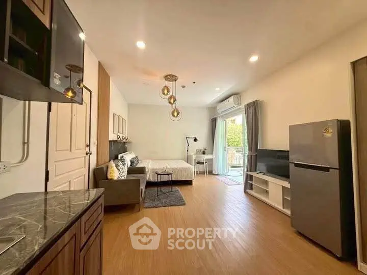 Spacious studio apartment with modern kitchen and cozy living area, featuring natural light and stylish decor.