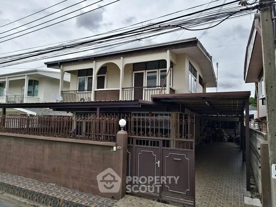 Charming two-story house with gated entrance and covered driveway in a suburban neighborhood.