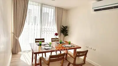 Bright dining area with modern table, chairs, and large window with city view.