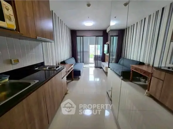 Modern living room with sleek kitchen and stylish decor, featuring a cozy sofa and elegant striped wallpaper.