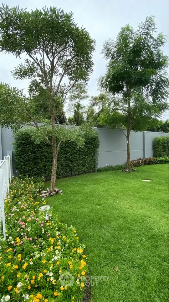 Lush green garden with vibrant flowers and trees, perfect for outdoor relaxation and enjoyment.