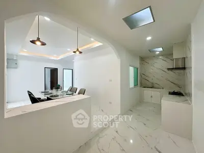 Modern open-layout kitchen and dining area with sleek marble flooring and contemporary lighting.
