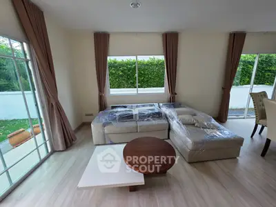 Spacious living room with large windows and modern furniture, offering a bright and inviting atmosphere.