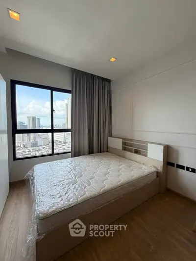 Modern bedroom with large window offering stunning city views, featuring a new bed and sleek wooden flooring.