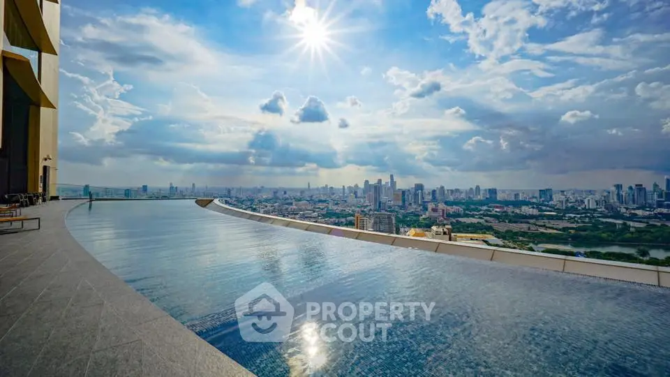 Stunning rooftop infinity pool with panoramic city skyline view under a bright blue sky.