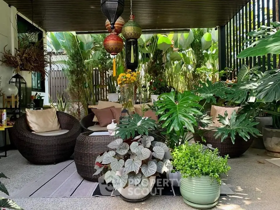 Charming outdoor patio with lush greenery and cozy seating area, perfect for relaxation and entertaining.