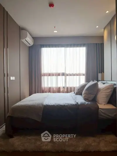 Luxurious bedroom with modern decor and large window offering natural light.