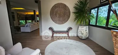 Spacious living area with modern decor and large windows offering lush greenery views.