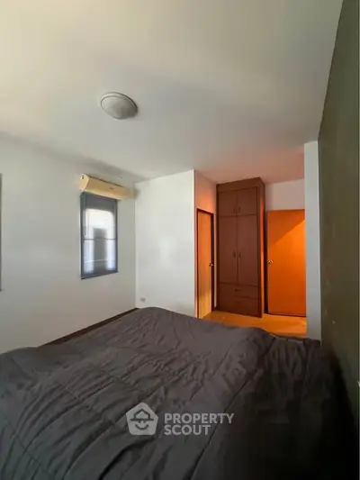 Cozy bedroom with built-in wardrobe and air conditioning unit.