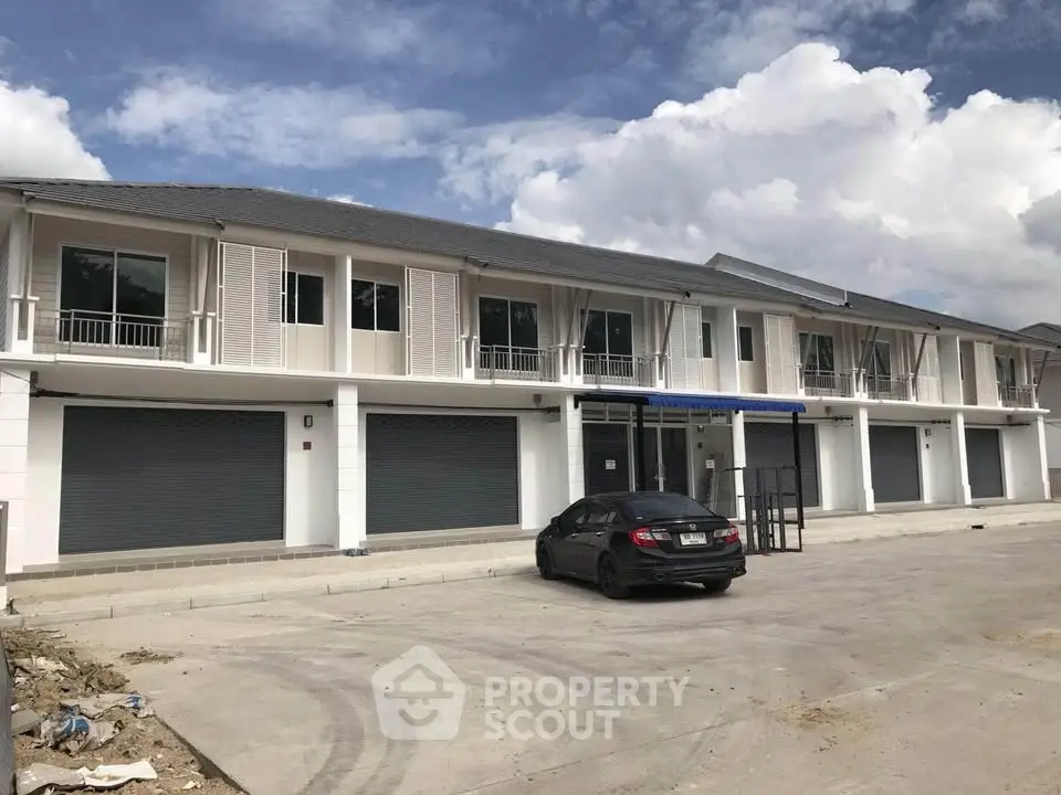 Modern townhouse complex with garage and parking space under a clear blue sky.