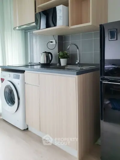 Modern compact kitchen with washing machine and microwave in stylish apartment