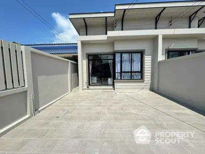 Modern single-story home with spacious tiled courtyard and sleek exterior design.