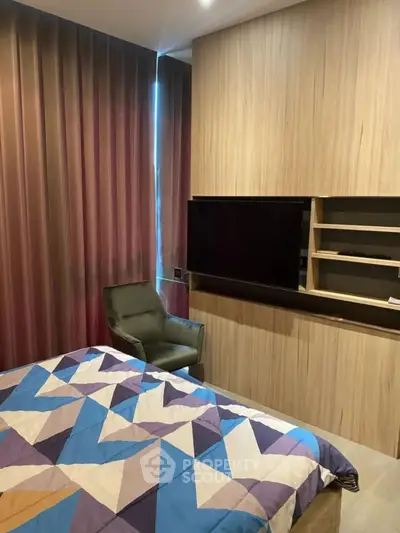 Modern bedroom with stylish decor and cozy ambiance, featuring a sleek TV setup and comfortable seating.
