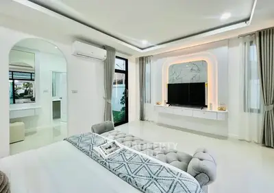Luxurious modern bedroom with elegant decor and large TV setup.