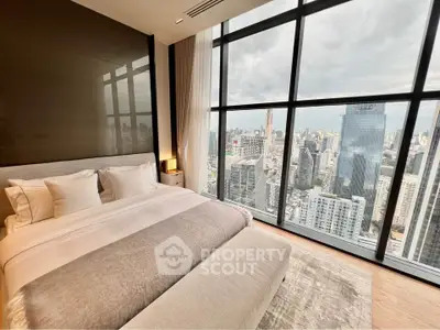 Luxurious bedroom with panoramic city view from floor-to-ceiling windows in high-rise apartment.