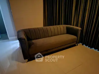 Elegant modern living room with stylish dark velvet sofa and floor-to-ceiling curtains.