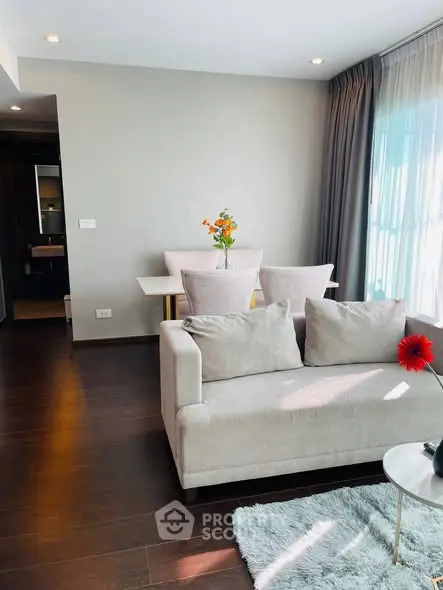 Modern living room with elegant decor and natural light, featuring a cozy sofa and dining area.