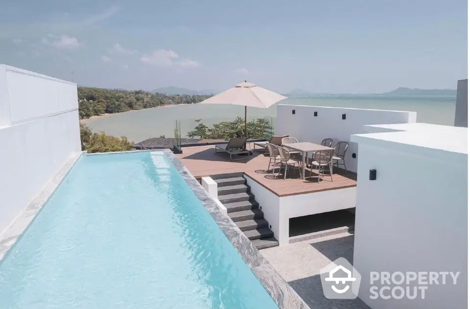 Stunning rooftop pool with ocean view and modern patio furniture.