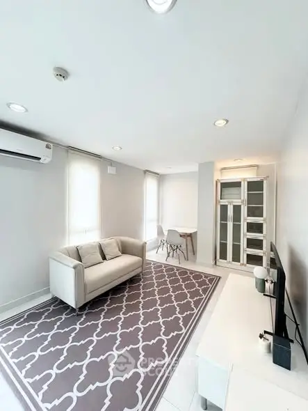 Modern living room with stylish decor, featuring a cozy sofa and elegant rug, perfect for relaxation.