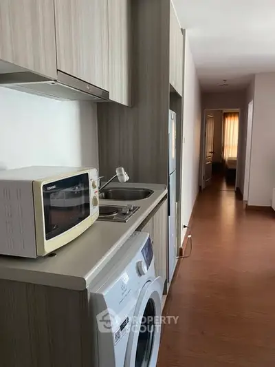 Modern kitchen with washing machine and microwave in sleek apartment