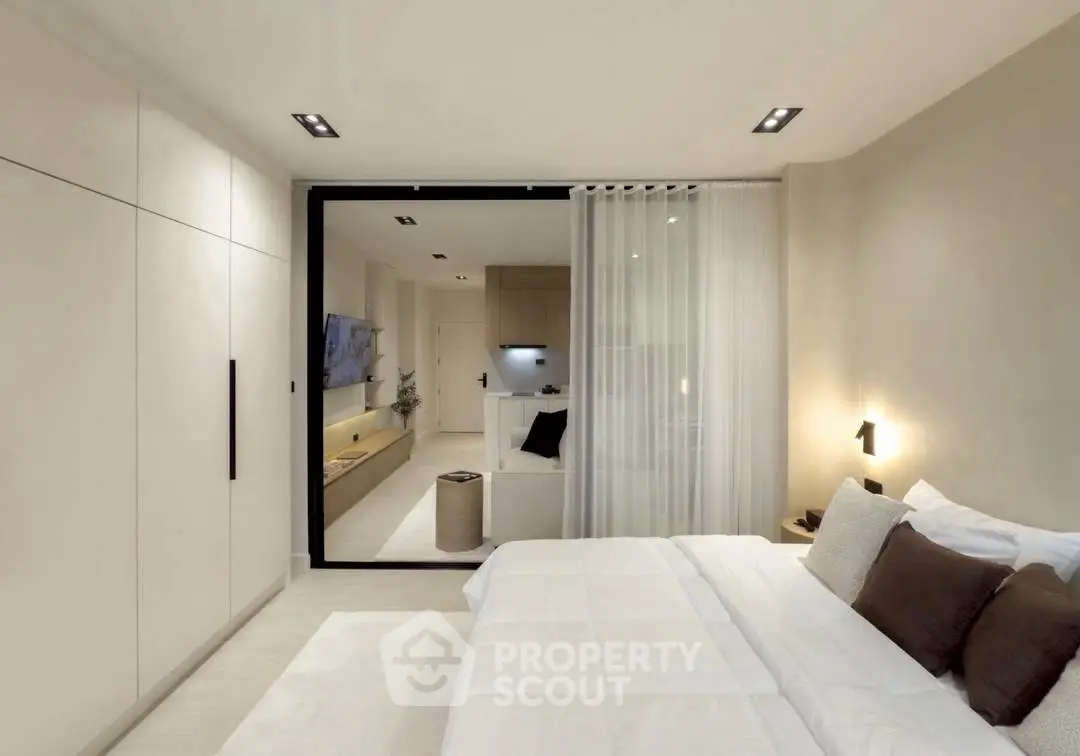 Modern bedroom with sleek design and open view to living area, featuring neutral tones and stylish lighting.