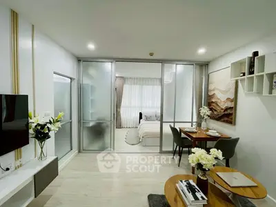 Modern open-plan living room with dining area and bedroom, featuring elegant decor and natural light.