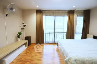 Spacious bedroom with wooden flooring and large windows for natural light