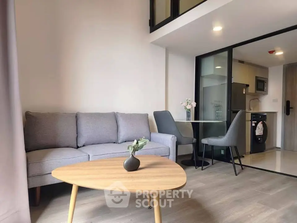 Modern living room with cozy sofa and stylish dining area in open-plan apartment.
