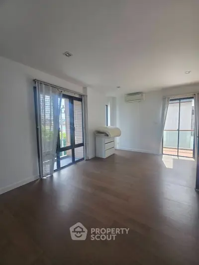 Spacious living room with large windows and wooden flooring in modern apartment.