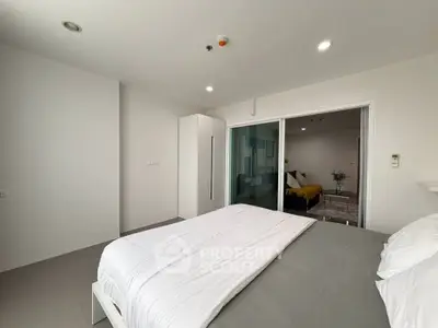Modern bedroom with minimalist design and sliding glass doors leading to a cozy living area.