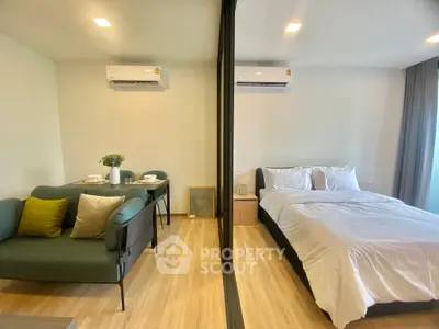 Modern studio apartment with cozy living area and comfortable bed, featuring stylish decor and ample natural light.