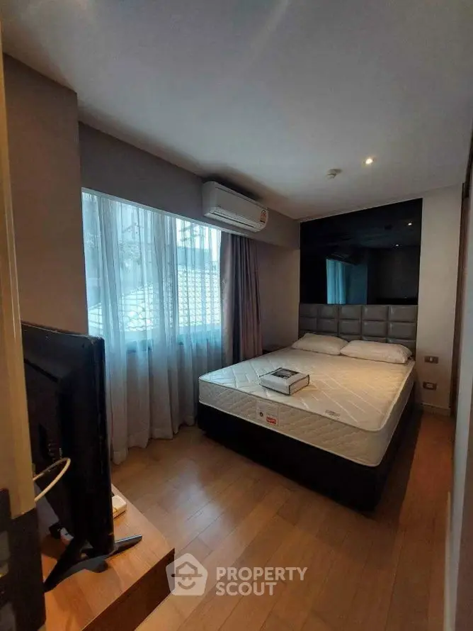 Cozy bedroom with modern decor and natural light, featuring a comfortable bed and sleek wooden flooring.