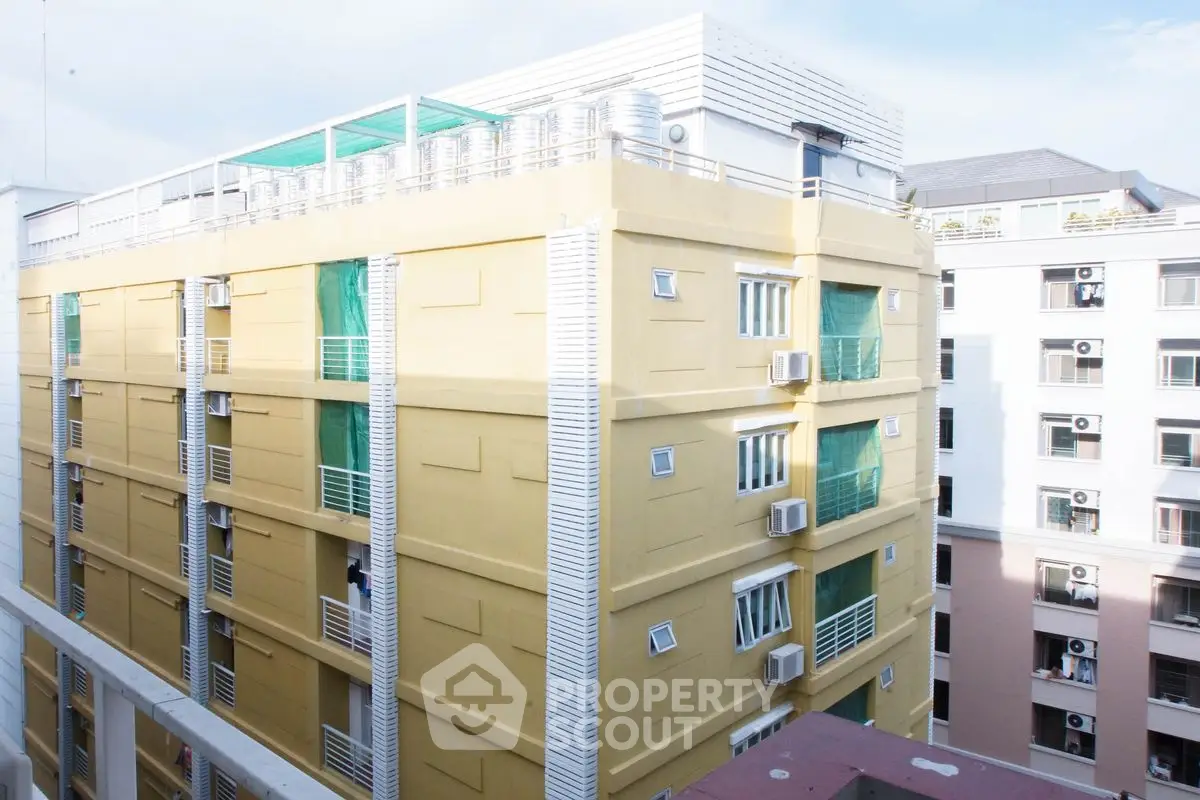Modern urban apartment building with rooftop terrace and vibrant exterior.